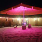 A pink umbrella is lit up in the night.