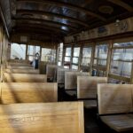 A wooden bus with many seats in it